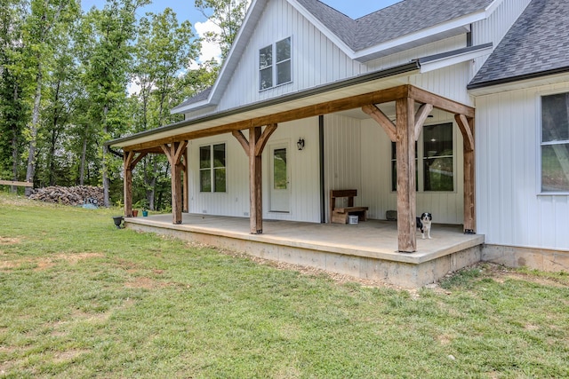 exterior space with a shingled roof, board and batten siding, and a yard