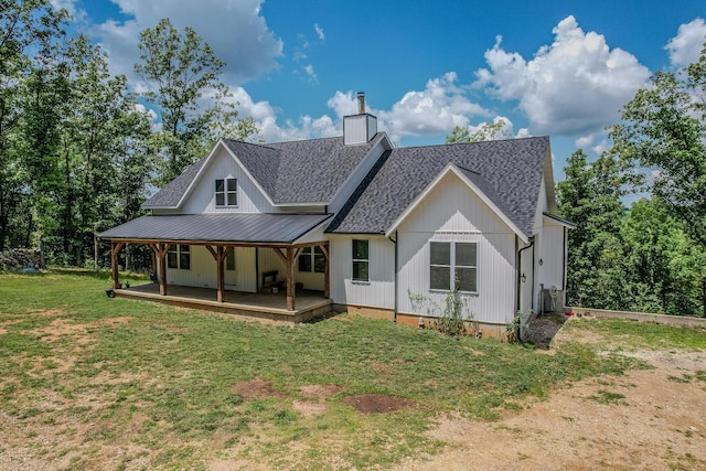 rear view of house with a lawn, a chimney, metal roof, roof with shingles, and a standing seam roof