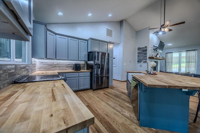 kitchen featuring visible vents, light wood-style flooring, black appliances, wood counters, and a kitchen breakfast bar