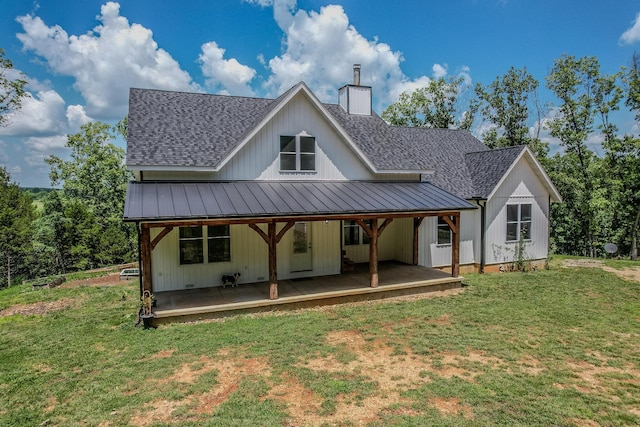 rear view of property with metal roof, a yard, roof with shingles, a standing seam roof, and a chimney