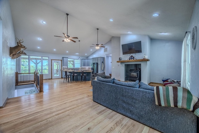 living area with recessed lighting, visible vents, light wood-style flooring, a wood stove, and high vaulted ceiling