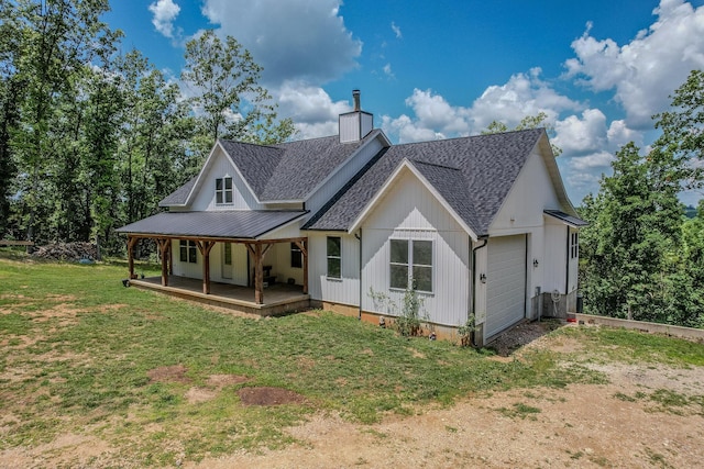 back of house featuring a shingled roof, a chimney, an attached garage, and a lawn