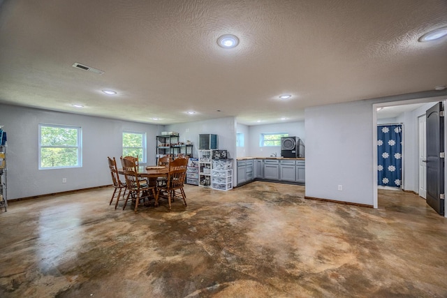 dining space featuring a textured ceiling, concrete floors, visible vents, and baseboards