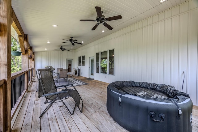 wooden deck with a ceiling fan, outdoor dining space, and a hot tub