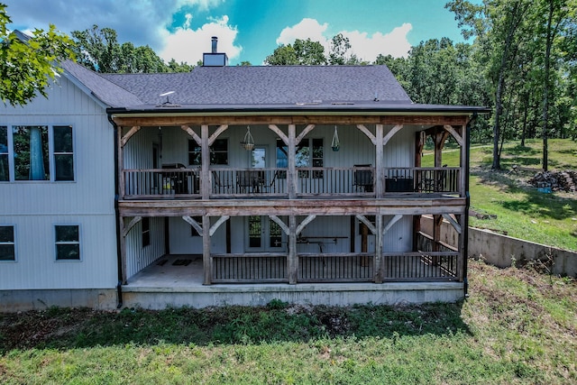 back of house with a patio area, a chimney, and roof with shingles