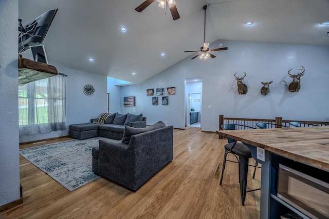 living area with a ceiling fan, high vaulted ceiling, and wood finished floors