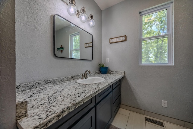 bathroom with a textured wall, vanity, and visible vents