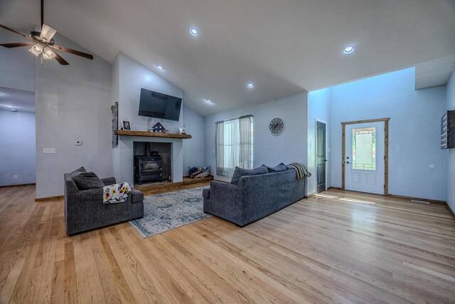 living area with high vaulted ceiling, recessed lighting, wood finished floors, a ceiling fan, and a wood stove