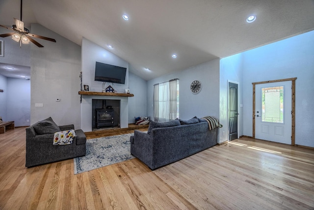 living area featuring a wood stove, high vaulted ceiling, and wood finished floors