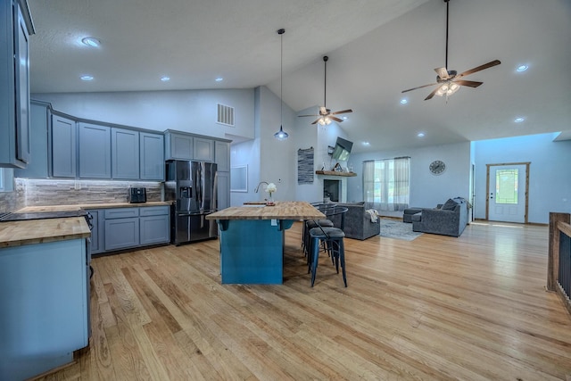 kitchen featuring butcher block countertops, a fireplace, black fridge, and open floor plan