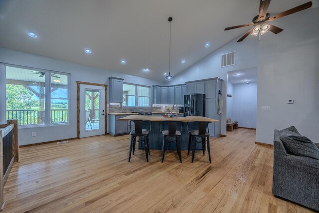 kitchen with a breakfast bar, visible vents, light countertops, black fridge, and light wood finished floors