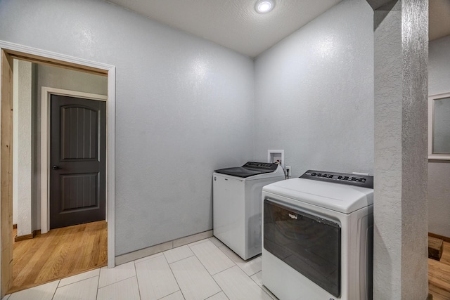 laundry room with washer and dryer, laundry area, and a textured wall