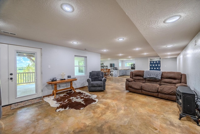 living area featuring finished concrete flooring, a textured ceiling, visible vents, and recessed lighting