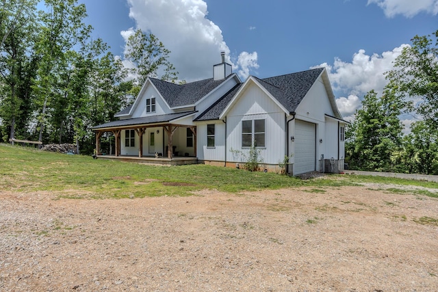 modern farmhouse style home with dirt driveway, a chimney, roof with shingles, an attached garage, and covered porch