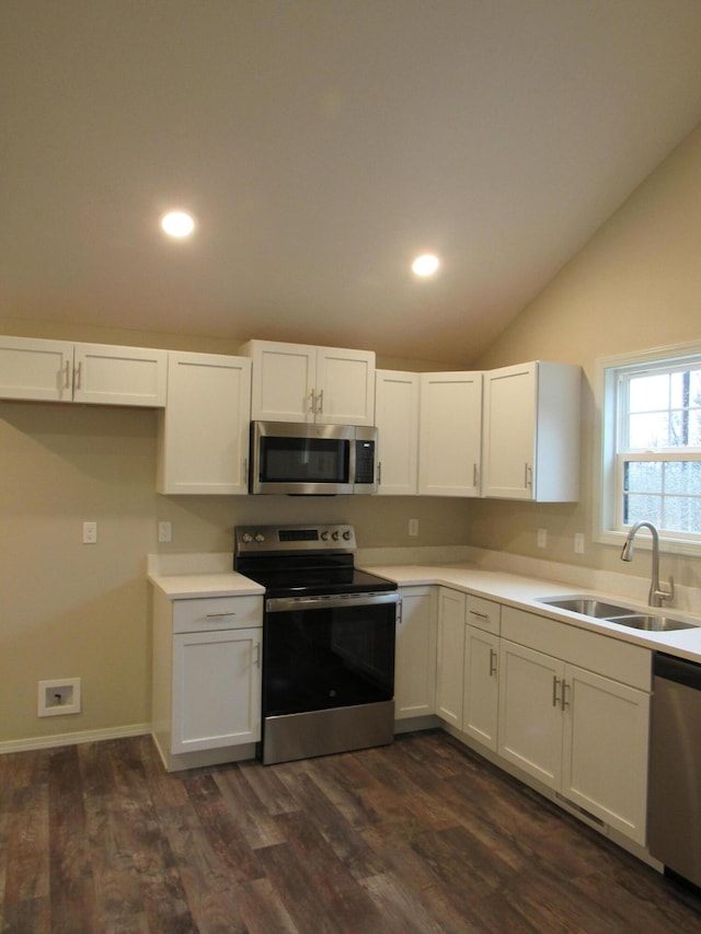 kitchen featuring vaulted ceiling, appliances with stainless steel finishes, a sink, and white cabinets