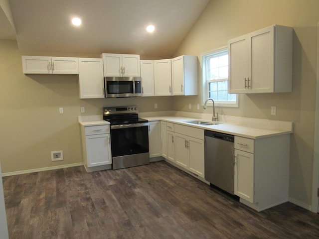 kitchen featuring lofted ceiling, stainless steel appliances, dark wood-type flooring, a sink, and white cabinets