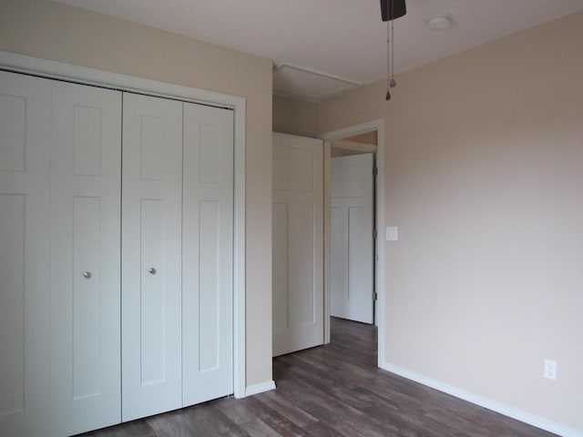 unfurnished bedroom featuring a ceiling fan, baseboards, dark wood finished floors, and a closet