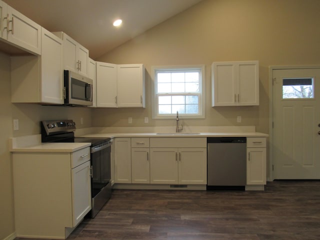 kitchen with white cabinets, lofted ceiling, light countertops, stainless steel appliances, and a sink