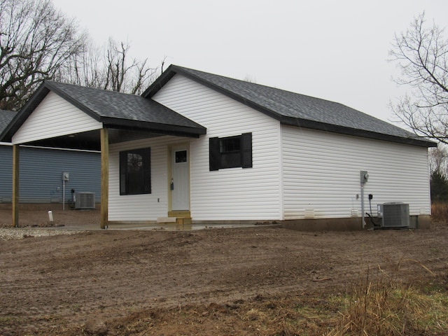 rear view of property with cooling unit and roof with shingles