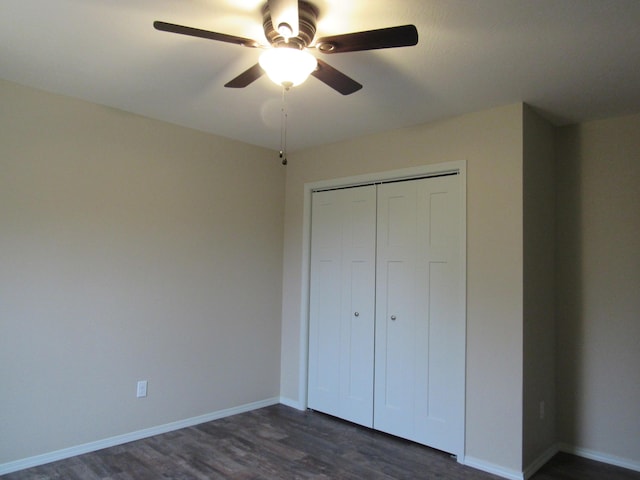 unfurnished bedroom featuring dark wood-style floors, a closet, a ceiling fan, and baseboards