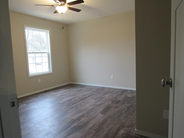 spare room with dark wood-type flooring, baseboards, and a ceiling fan