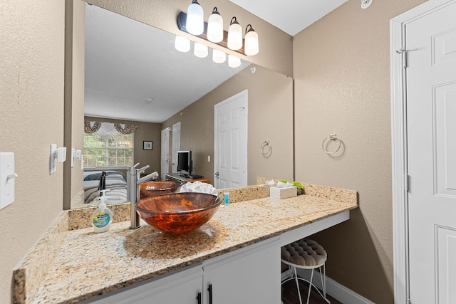 bathroom featuring vanity, baseboards, and a textured wall