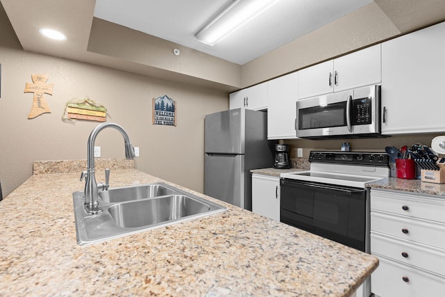 kitchen with recessed lighting, a textured wall, white cabinets, stainless steel appliances, and a sink