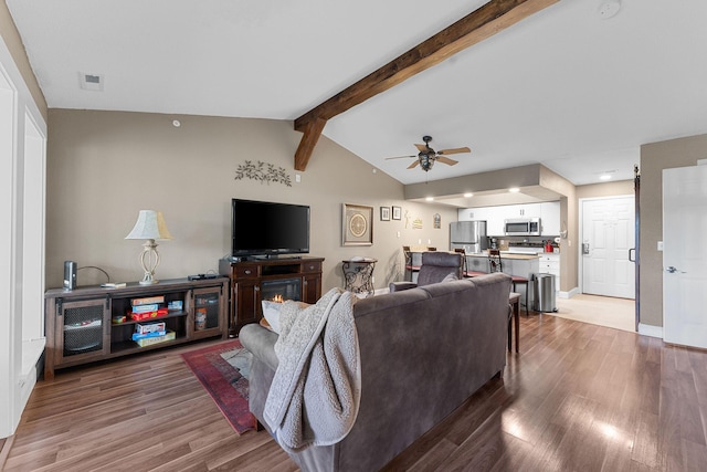 living room featuring visible vents, a ceiling fan, wood finished floors, baseboards, and vaulted ceiling with beams