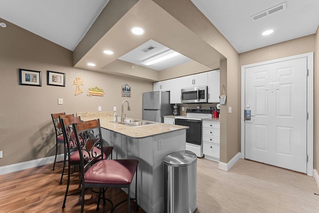 kitchen featuring visible vents, appliances with stainless steel finishes, a breakfast bar, and a peninsula