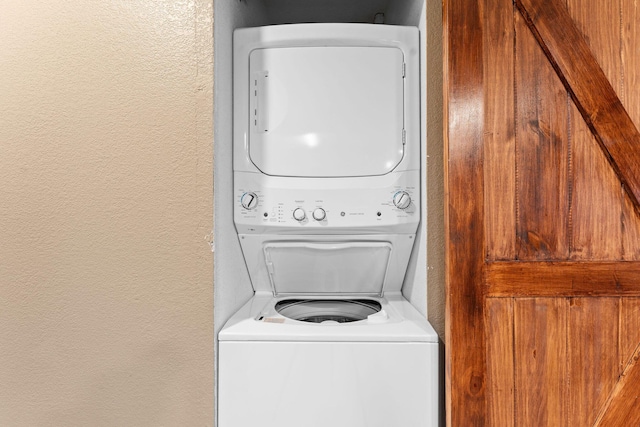 laundry room with a textured wall, laundry area, and stacked washing maching and dryer