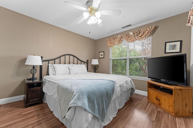 bedroom featuring ceiling fan, wood finished floors, visible vents, and baseboards