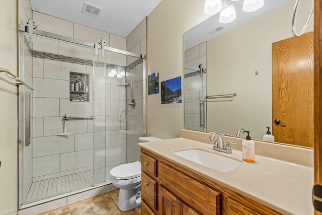 bathroom featuring toilet, vanity, a shower stall, and visible vents