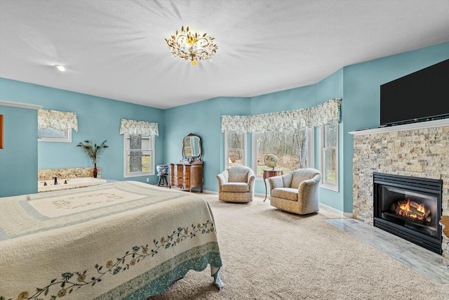 carpeted bedroom featuring a stone fireplace and baseboards