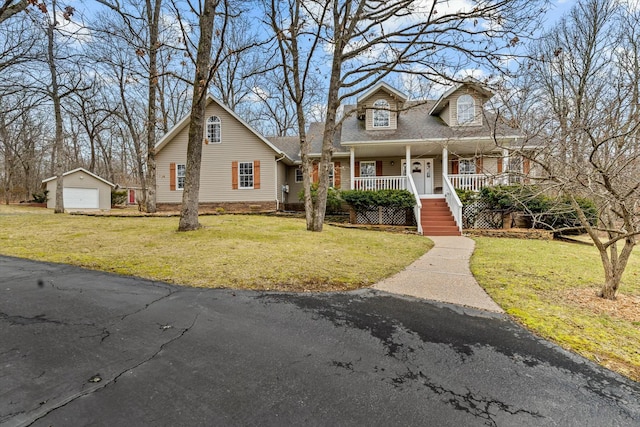 view of front of house with a porch, an outbuilding, a detached garage, and a front lawn