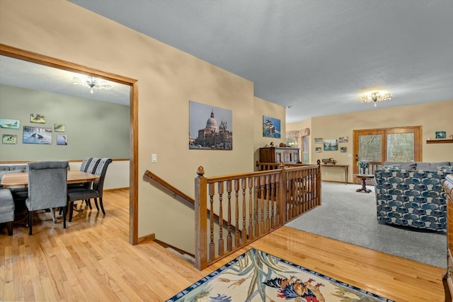 hall featuring baseboards, wood finished floors, and an upstairs landing