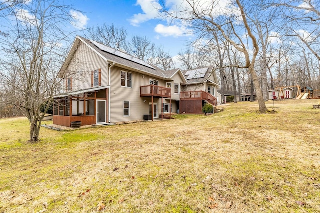 rear view of house with solar panels, central AC, a sunroom, a yard, and a wooden deck