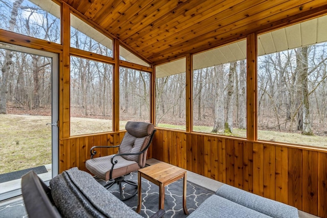 sunroom with a healthy amount of sunlight, wooden ceiling, vaulted ceiling, and a view of trees