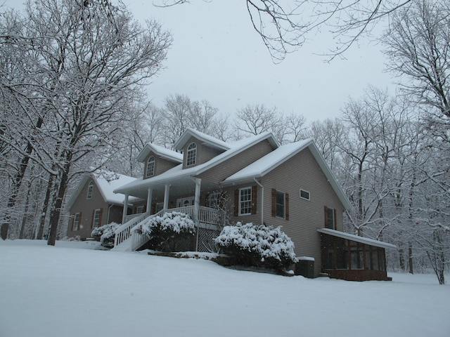 snow covered property featuring covered porch and central AC