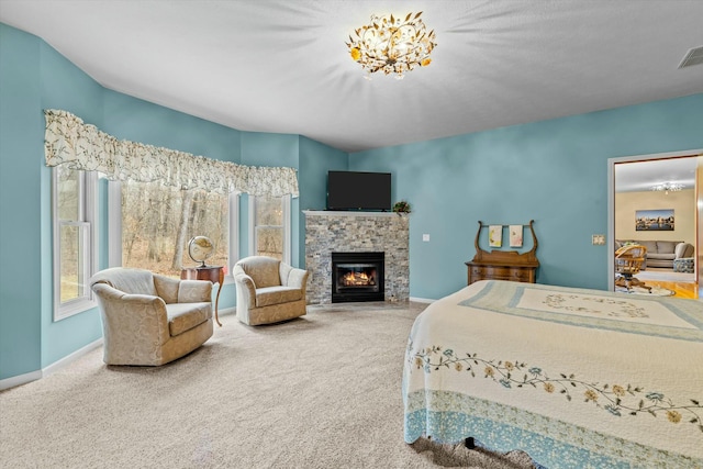 bedroom featuring multiple windows, visible vents, carpet flooring, and a stone fireplace