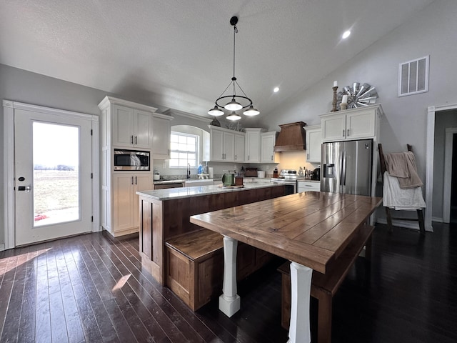 kitchen with a kitchen island, visible vents, appliances with stainless steel finishes, dark wood-style floors, and custom range hood