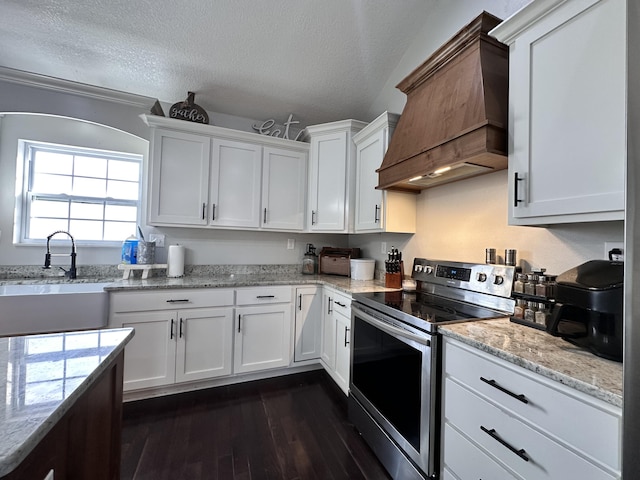 kitchen with white cabinetry, stainless steel electric range, custom exhaust hood, and a textured ceiling