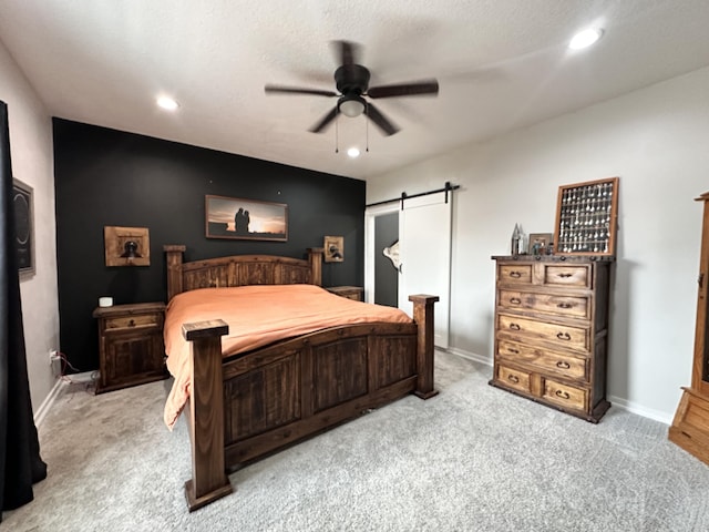 bedroom featuring light carpet, a barn door, baseboards, and recessed lighting