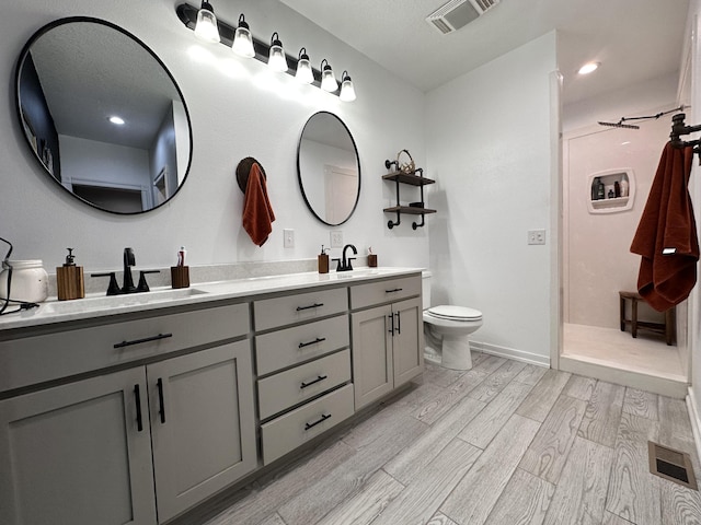 bathroom with double vanity, visible vents, a sink, and wood finished floors