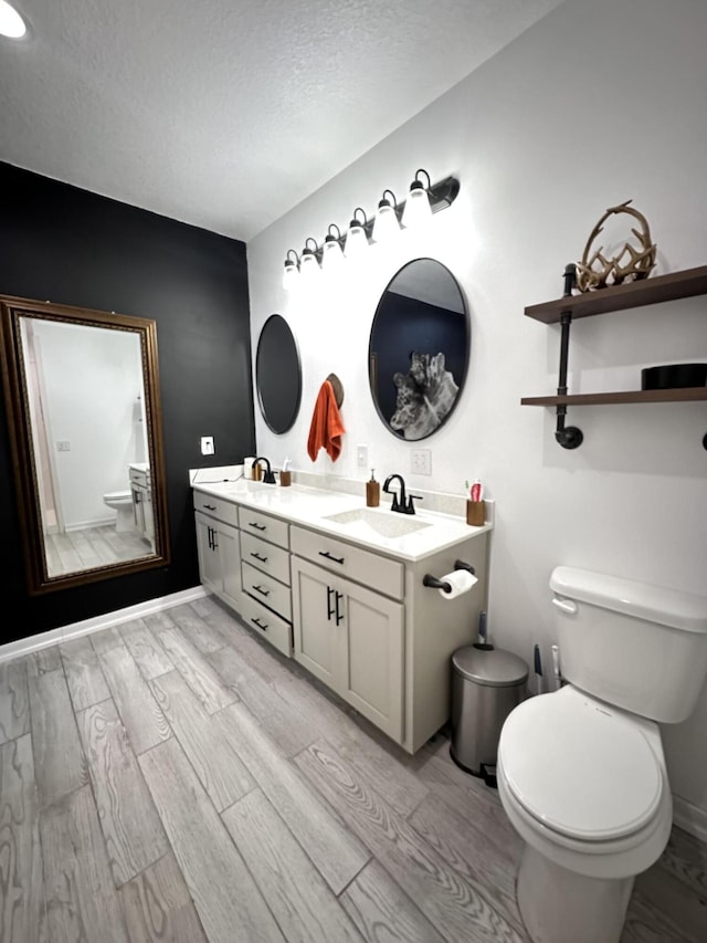 full bathroom with a sink, a textured ceiling, toilet, and wood finished floors