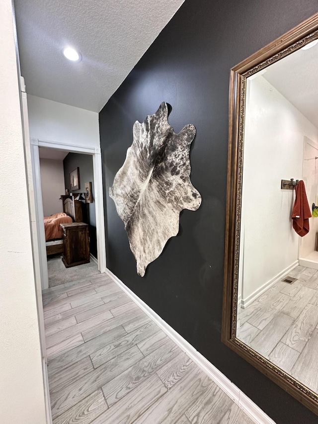 corridor with a textured ceiling, recessed lighting, wood finished floors, and baseboards