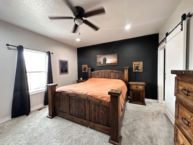 bedroom with baseboards, a barn door, a ceiling fan, and light colored carpet