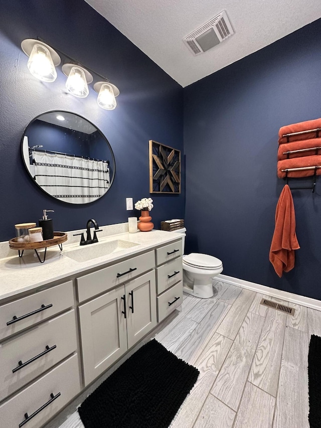 bathroom featuring toilet, wood finish floors, vanity, and visible vents