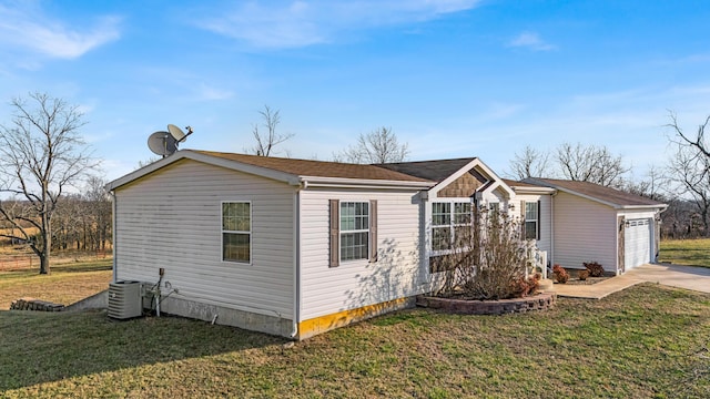 view of front of property featuring a garage, concrete driveway, a front lawn, and central AC unit