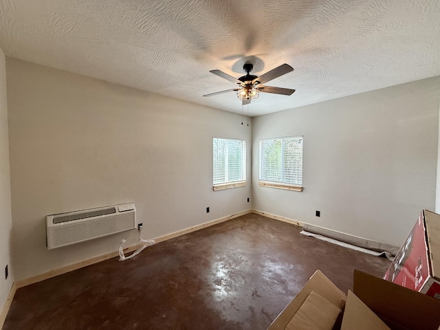 empty room with concrete flooring, ceiling fan, a textured ceiling, baseboards, and a wall mounted air conditioner