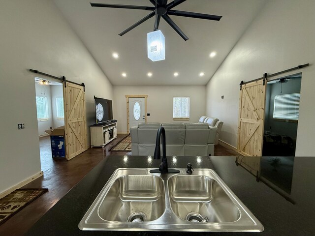 kitchen with a ceiling fan, a barn door, high vaulted ceiling, and a sink